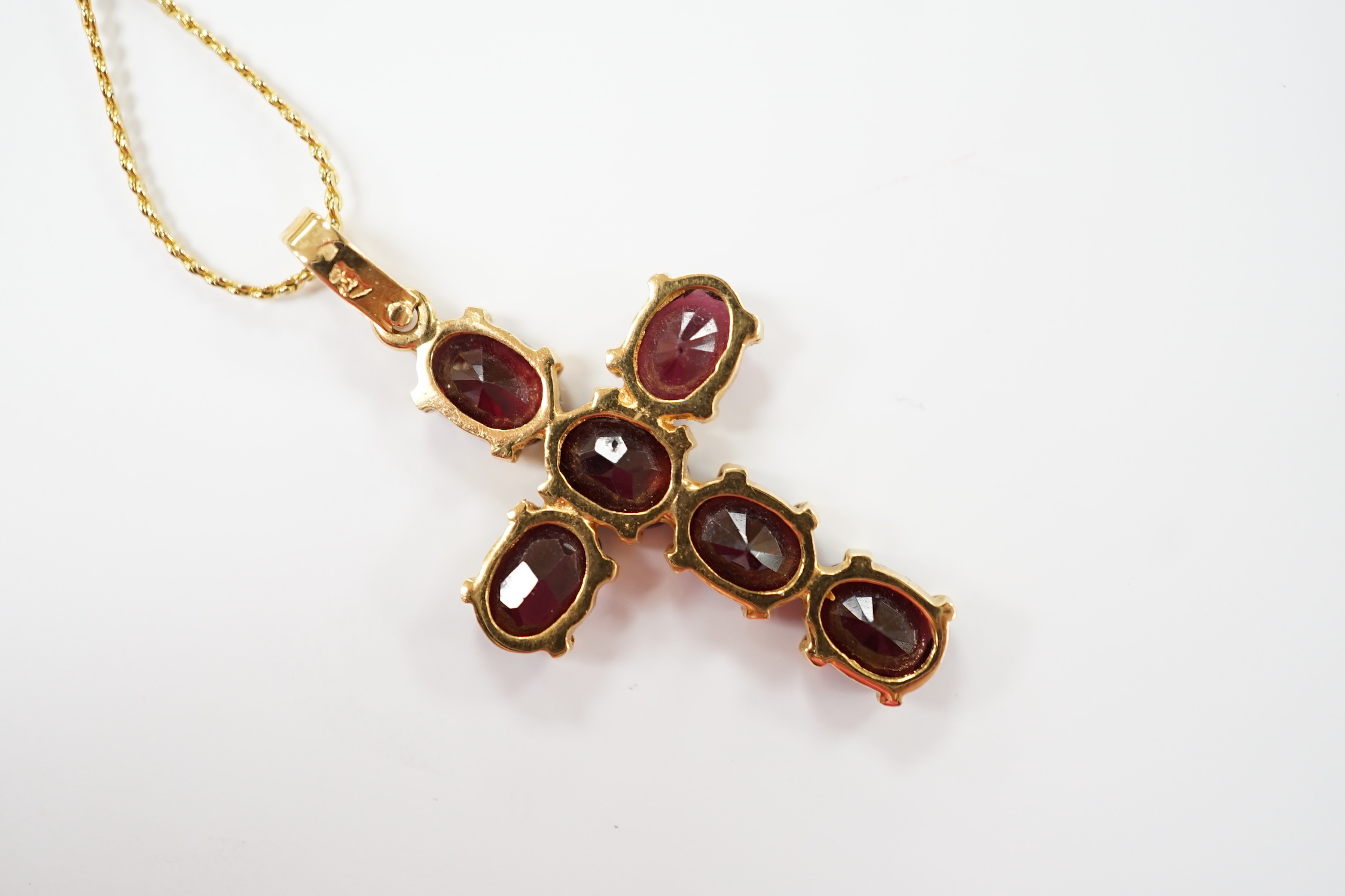 A modern 750 yellow metal and six stone oval cut garnet set cross pendant, 38mm, gross weight 3.5 grams, on a gilt metal chain.